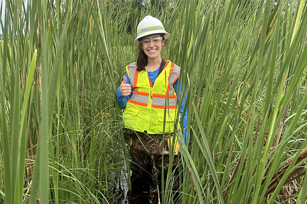 Knee deep in a bog, water resources intern Josie Hartman helps with mid-season TROLL data downloads.