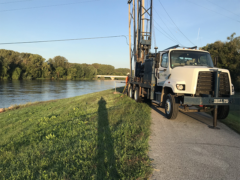 A drill rig is positioned on a sidewalk along the riverbank of the Des Moines River. Geotechnical investigations along the Des Moines River informed the design and modeling for slope stability and seepage. Barr consulted with the U.S. Army Corps of Engineers to gain approval of the drilling plan prior to beginning investigations.