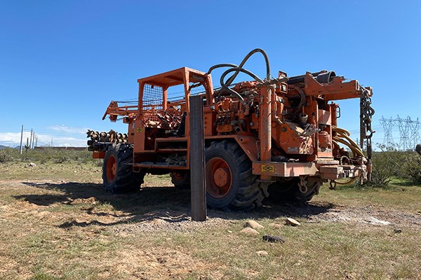 A drill rig parked next to a steel test pile in an Arizona desert.
