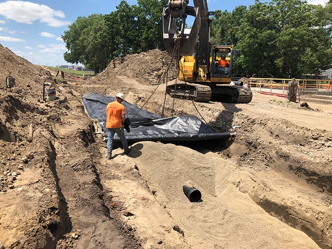A large cement pipe being buried in the ground.