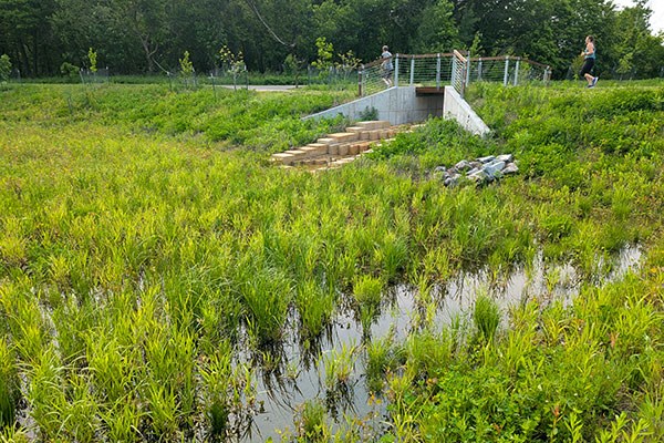 The entrance to Hasenbank Stormwater Park, containing a sign and bike racks.