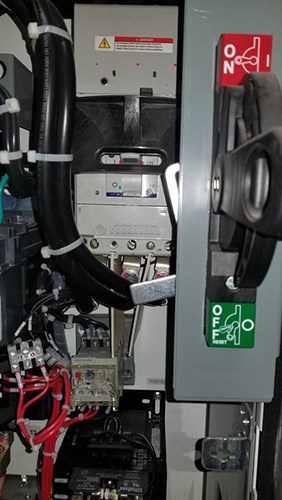 Electrical panel with multiple components and wiring, featuring a large switch labeled ON and OFF in the ON position, along with warning labels and connected cables.